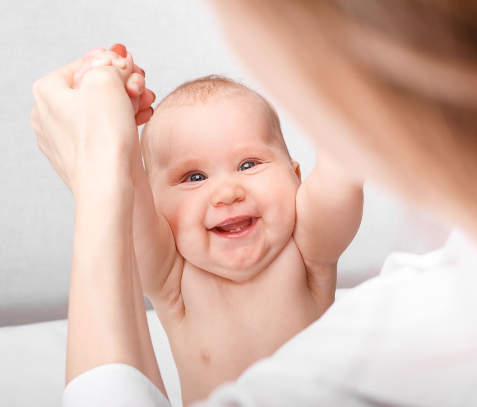 Lachendes Baby greift die Hände der Therapeutin